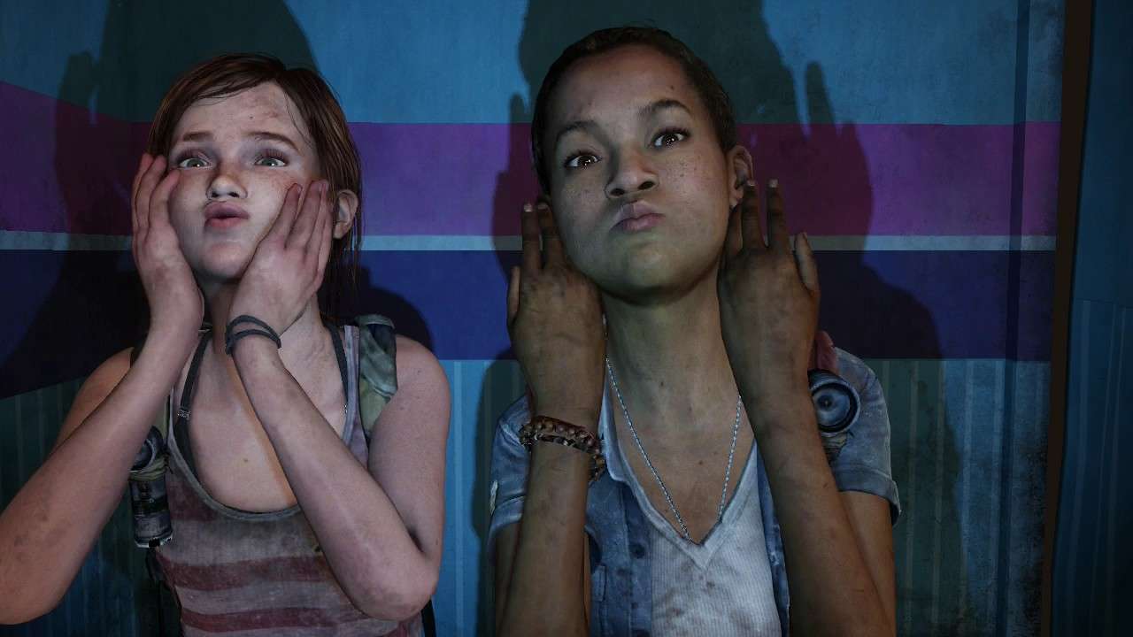 Ellie (left) and Riley (right) in a scene from the TLOU DLC, 'Left Behind' (2014). Ellie is a white teenage girl with long brown hair in a ponytail. She's wearing a red and white striped tank top and has a green backpack on with a black flashlight affixed to a strap. She has black bracelets on one wrist, and is squishing her face with her hands to make a funny face. Riley is a Black teenage girl with her dark hair pulled back into a bun. She's wearing a denim short-sleeved buttondown open over a white v-neck shirt and dogtags around her neck. She has beaded bracelets on one wrist and presses the sides of her hands against each cheek mimicking fish gills as she puffs up her cheeks to make a funny face. They are in a photo booth dong silly poses. 