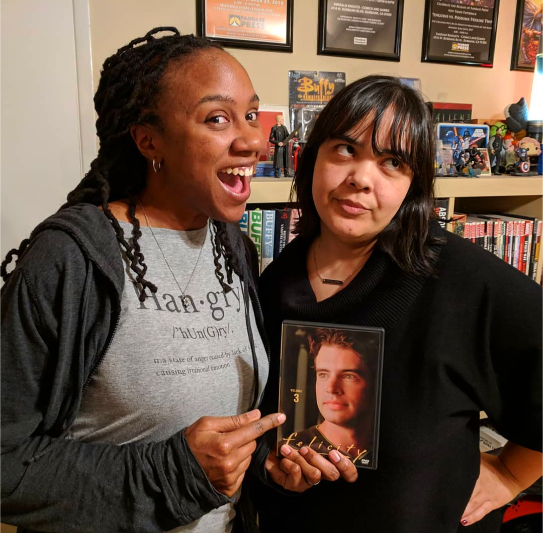 A Black woman and a brown Latina standing next to each other in an office. 