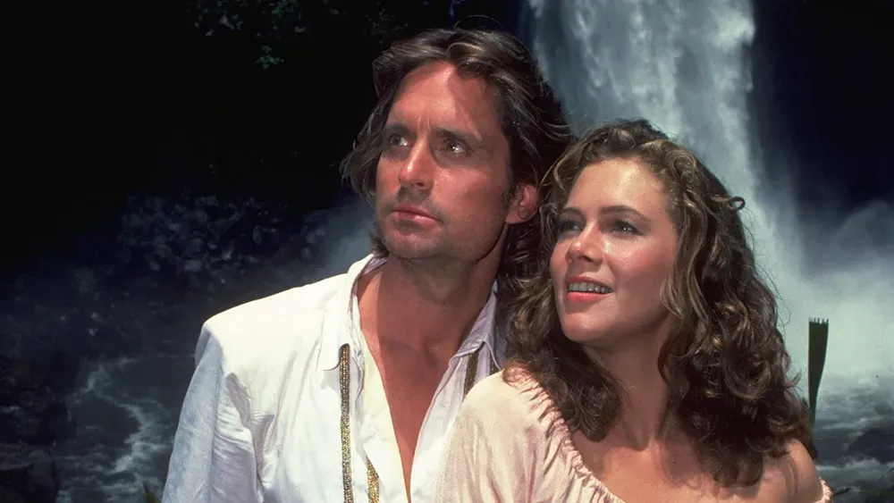 Image of Michael Douglass and Kathleen Turner in a scene from 'Romancing the Stone' standing in front of a waterfall.