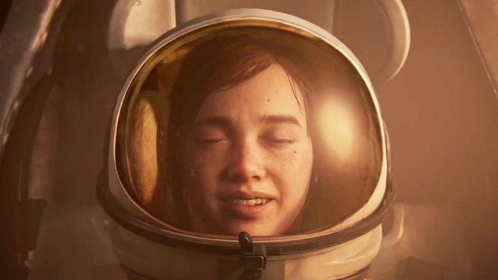 Close-up of Ellie wearing a space helmet as she sits in a NASA rover in a museum. Her eyes are closed, there's a smile on h